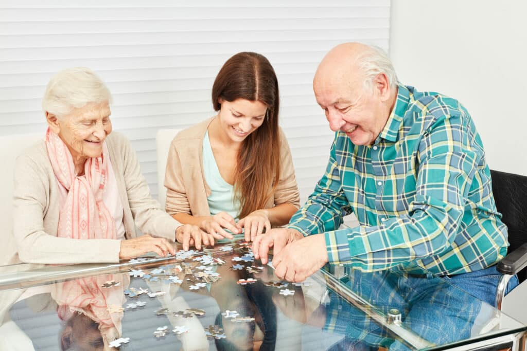 Family with seniors and granddaughter have fun playing puzzle at home