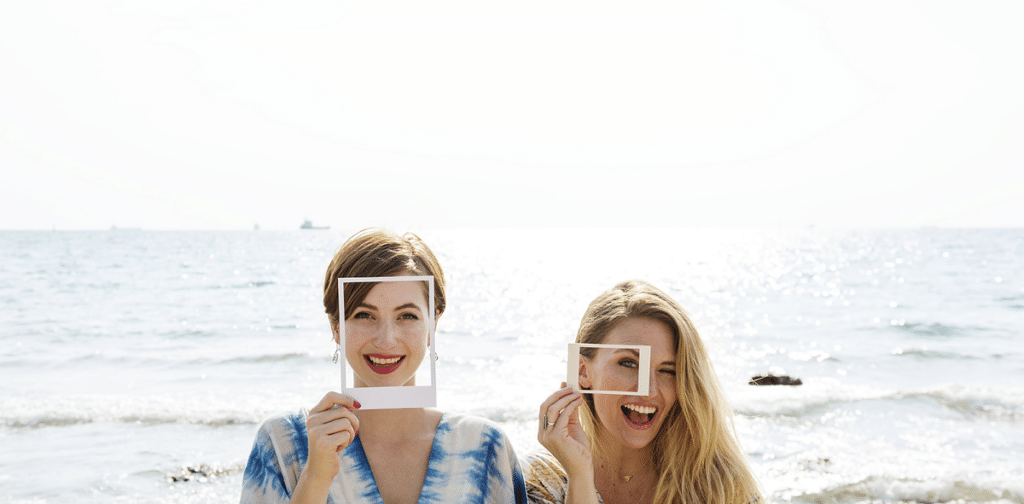 Women at the beach looking through polaroid picture cutouts