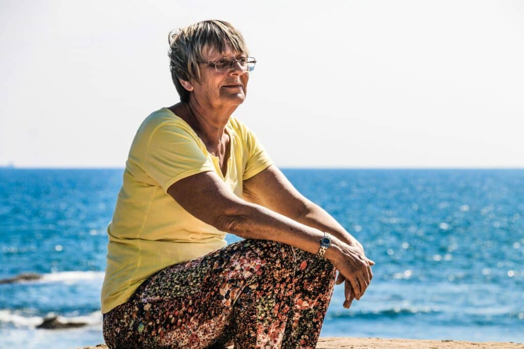 Older woman sitting by the sea